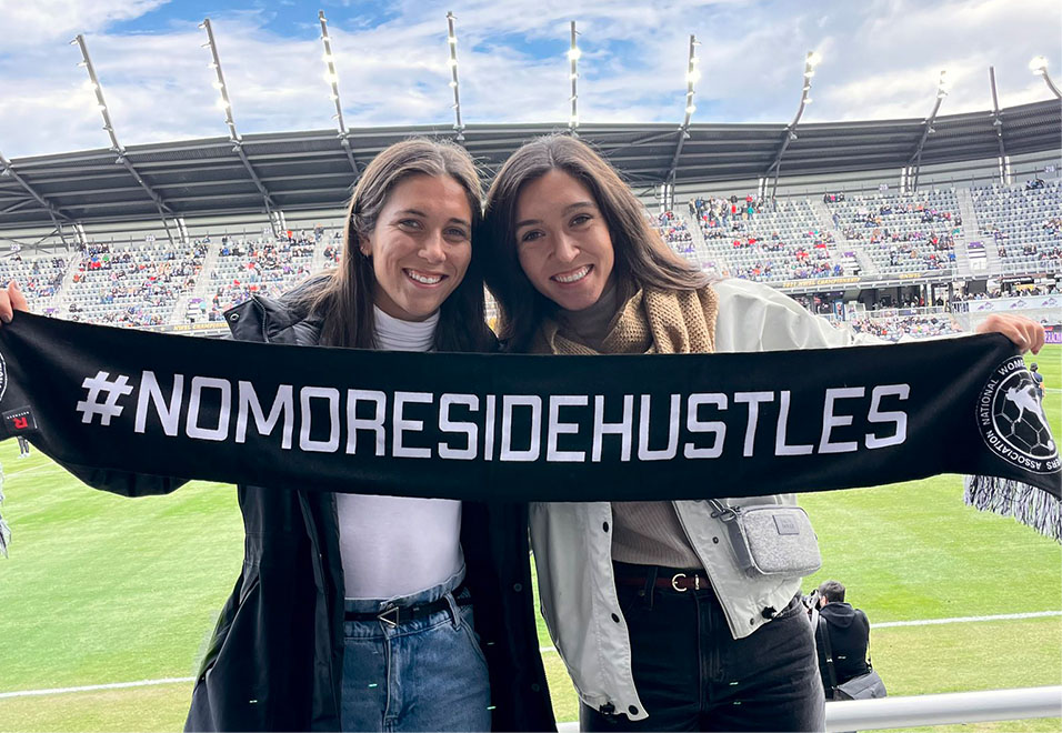 Sisters holding up a #NoMoresidehustles scarf